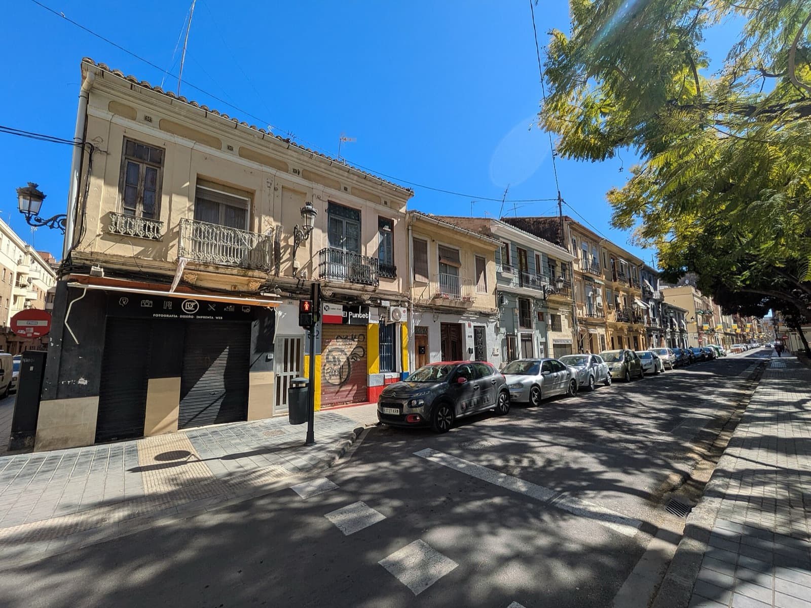 Maisons anciennes à un étage, balcons en fer forgé et arbres d’alignement le long du carrer de la Indústria, à Aiora (Valencia)