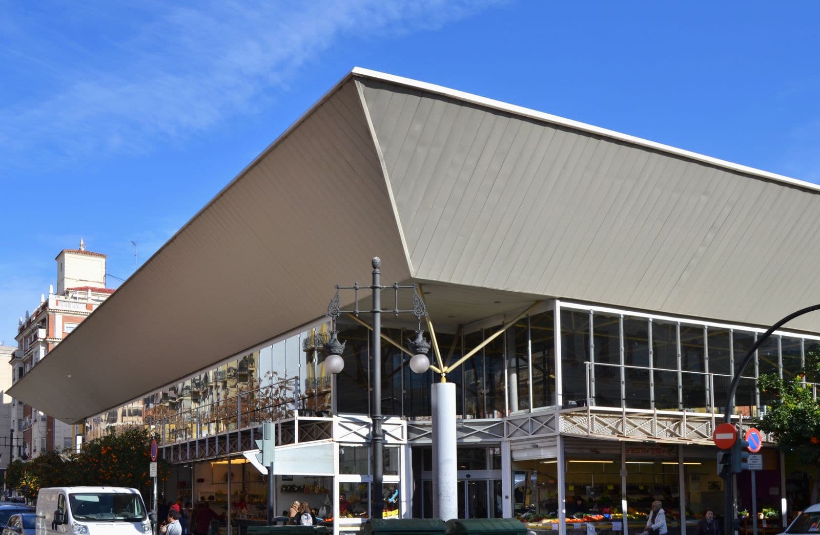 Le marché municipal de Jesús à Valencia : grande toiture en pointe au-dessus des étals vitrés, immeubles d’habitation à gauche, ciel bleu