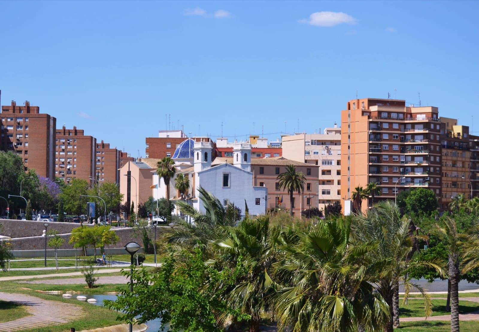 L’église de Mont-Olivet, sa coupole bleue et ses deux tours entre des immeubles d’habitation, vue depuis le jardin du Turia (Valencia)