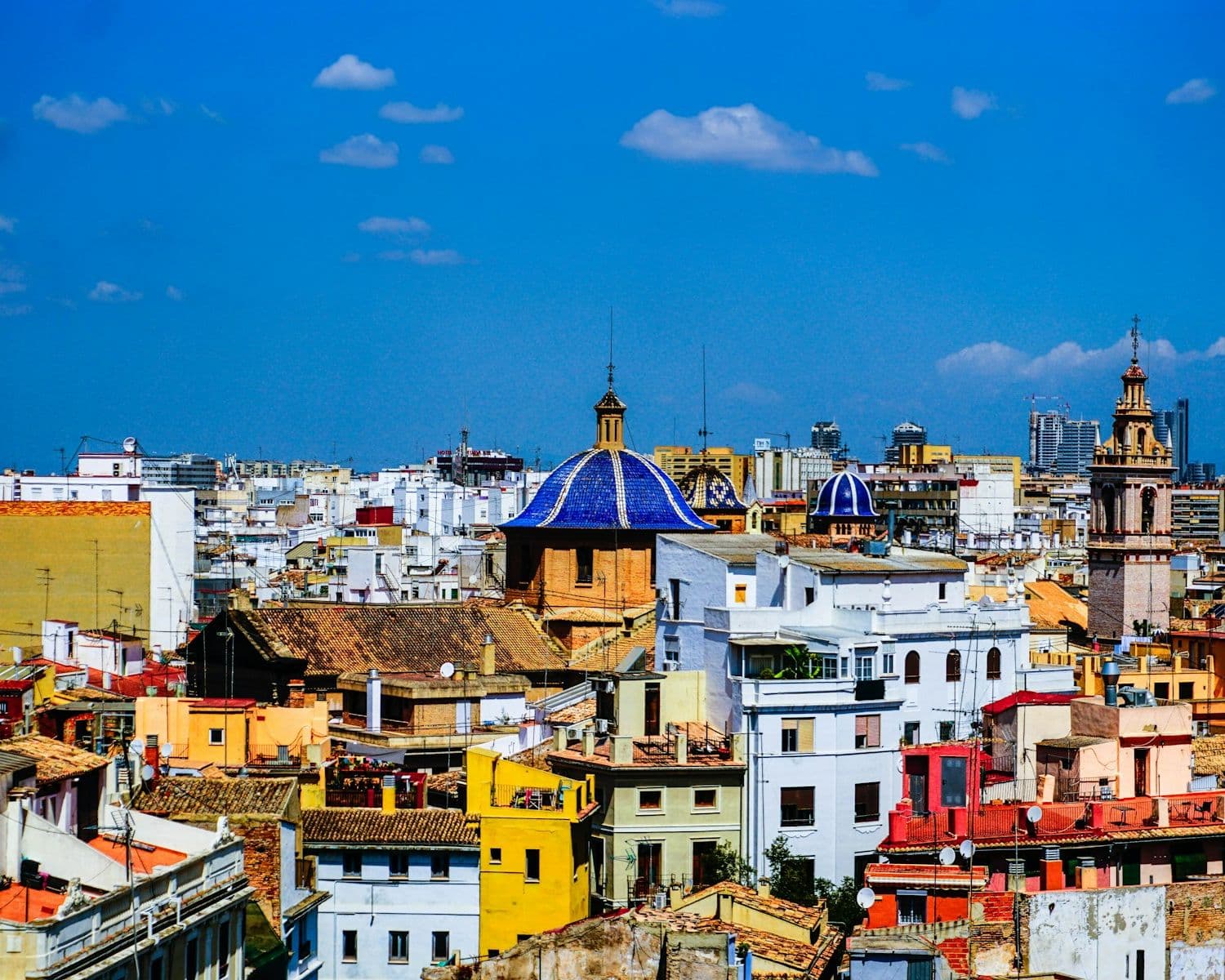 Toits et terrasses d’immeubles du centre de Valencia autour d’une coupole de tuiles bleues, vus depuis une tour