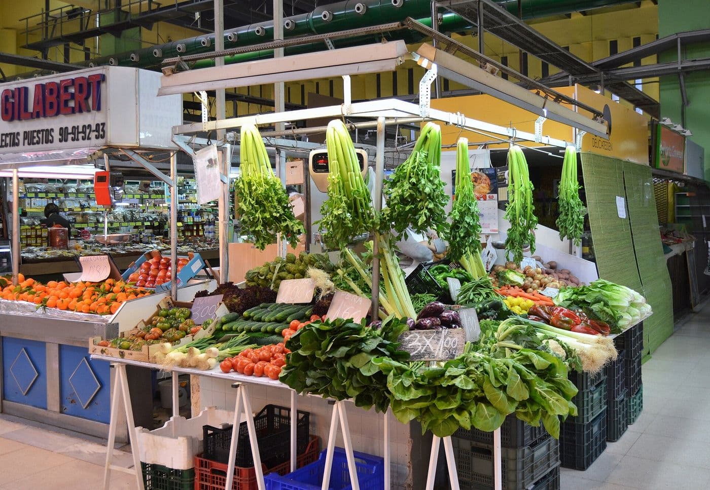 Un étal de fruits et légumes, céleris suspendus et oranges, au marché de Russafa à Valencia