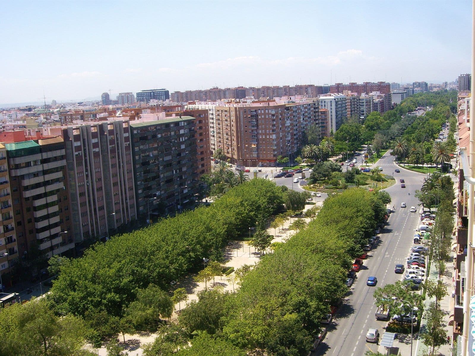 L’avenue Blasco Ibáñez vue d’un immeuble : large terre-plein central planté d’arbres, rond-point et immeubles d’habitation en brique (Valencia)
