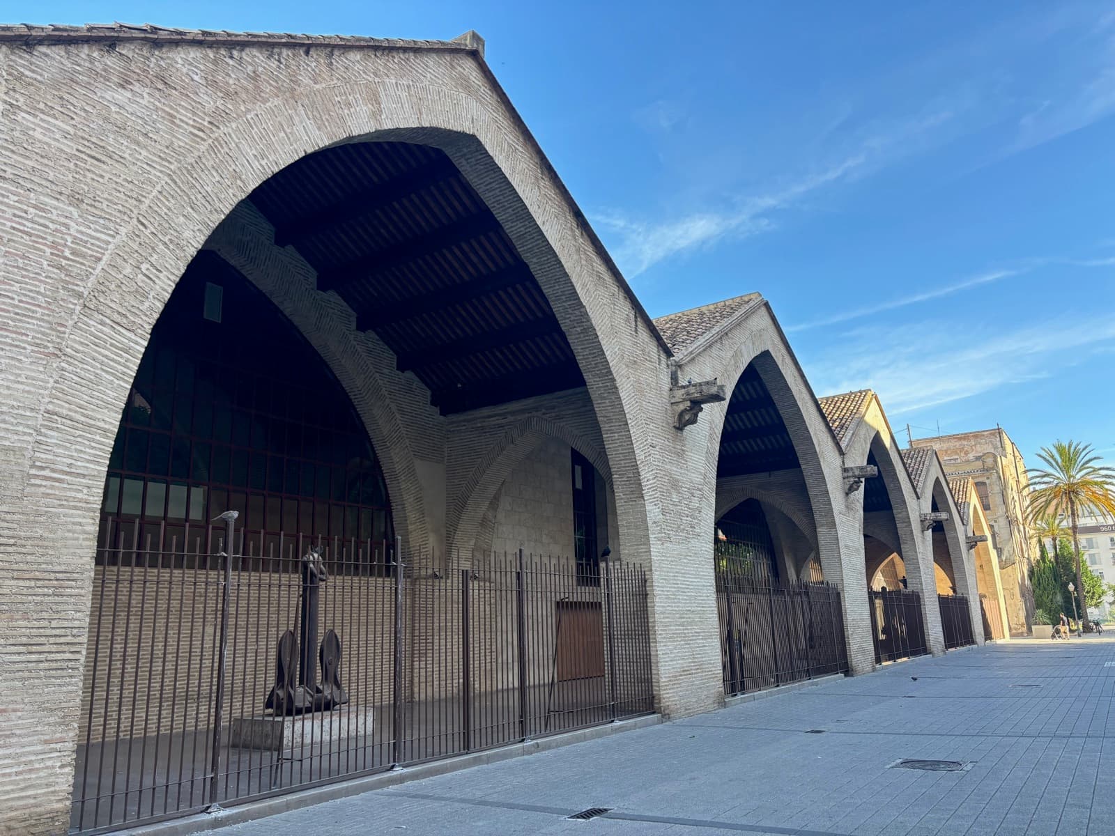 Les grands arcs gothiques en brique des Drassanes, les anciens chantiers navals du Grau, le long d’une rue piétonne (Valencia)