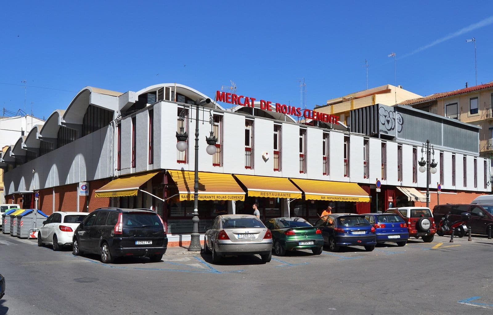 Le marché municipal de Rojas Clemente, bâtiment blanc à toiture ondulée et stores jaunes, sur sa place du Botànic (Valencia)