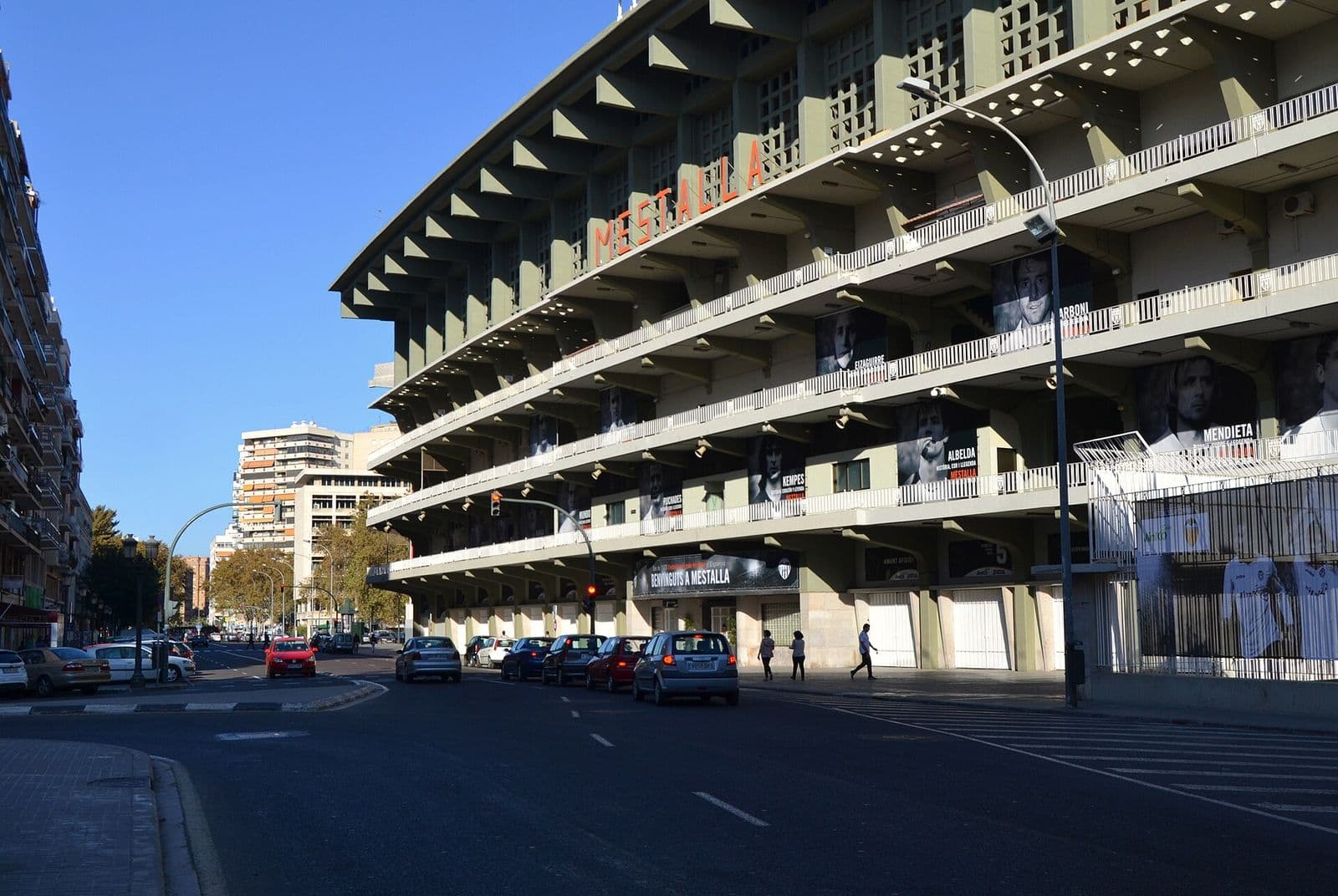 Façade du stade de Mestalla, son nom en grandes lettres rouges, le long de l’avenue de Suecia, avec des immeubles d’habitation au fond (Valencia)
