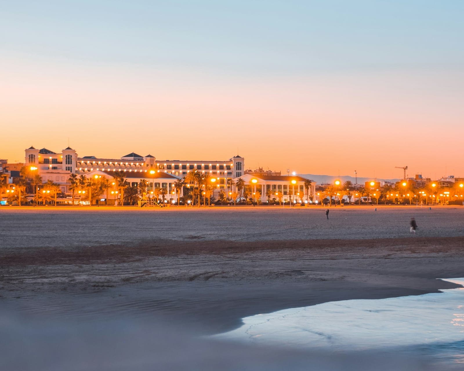 La plage de Las Arenas à Valencia au crépuscule, promenade maritime illuminée et promeneurs au loin